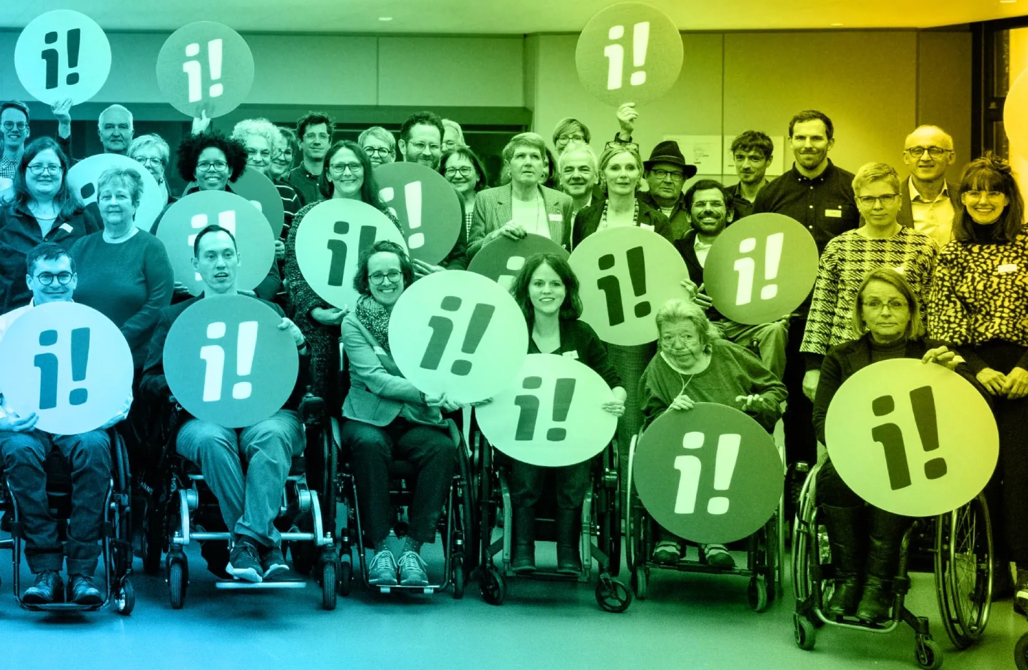 Gruppenbild: Rund vierzig Menschen, viele im Rollstuhl, halten runde Schilder mit dem Logo der Inklusions-Initiative hoch