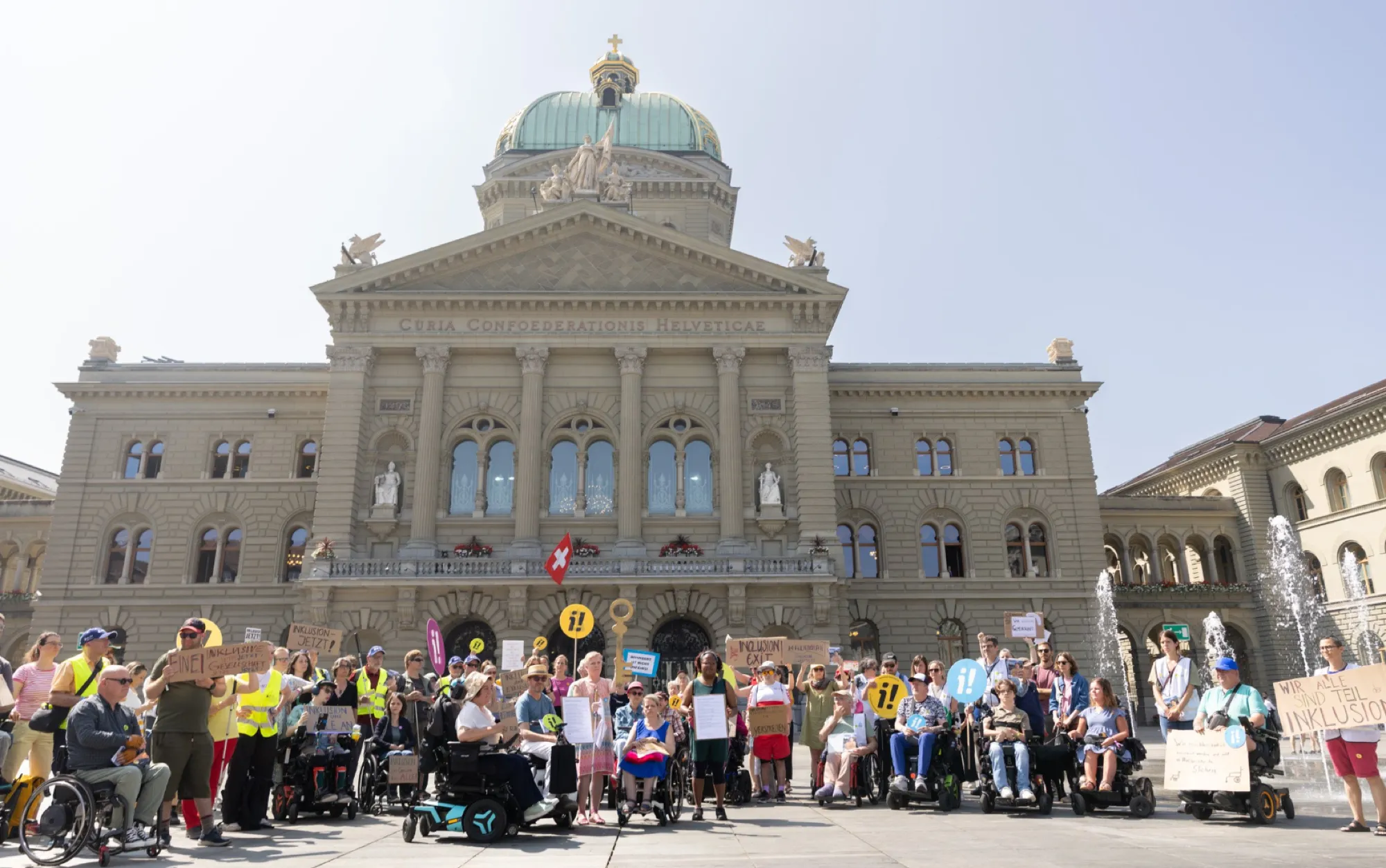 Kundgebung vor dem Bundeshaus: viele Menschen, einige im Rollstuhl, mit Transparenten und Schildern der Inklusions-Initiative