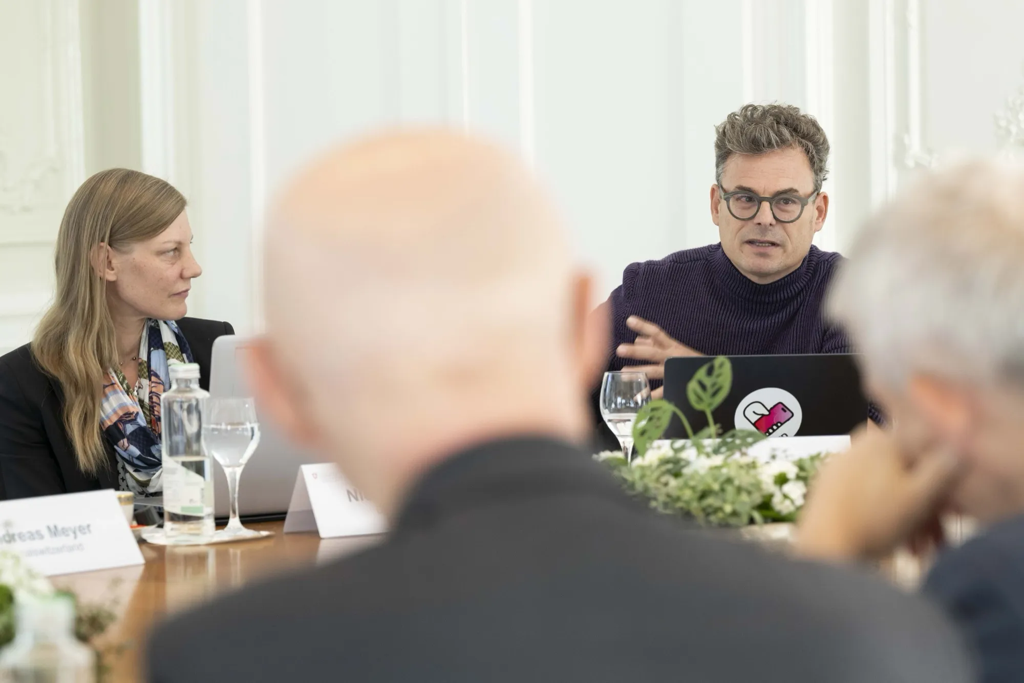 Daniel Graf spricht am Beiratstreffen, neben ihm eine Teilnehmerin, im Vordergrund unscharf ein Zuhörer